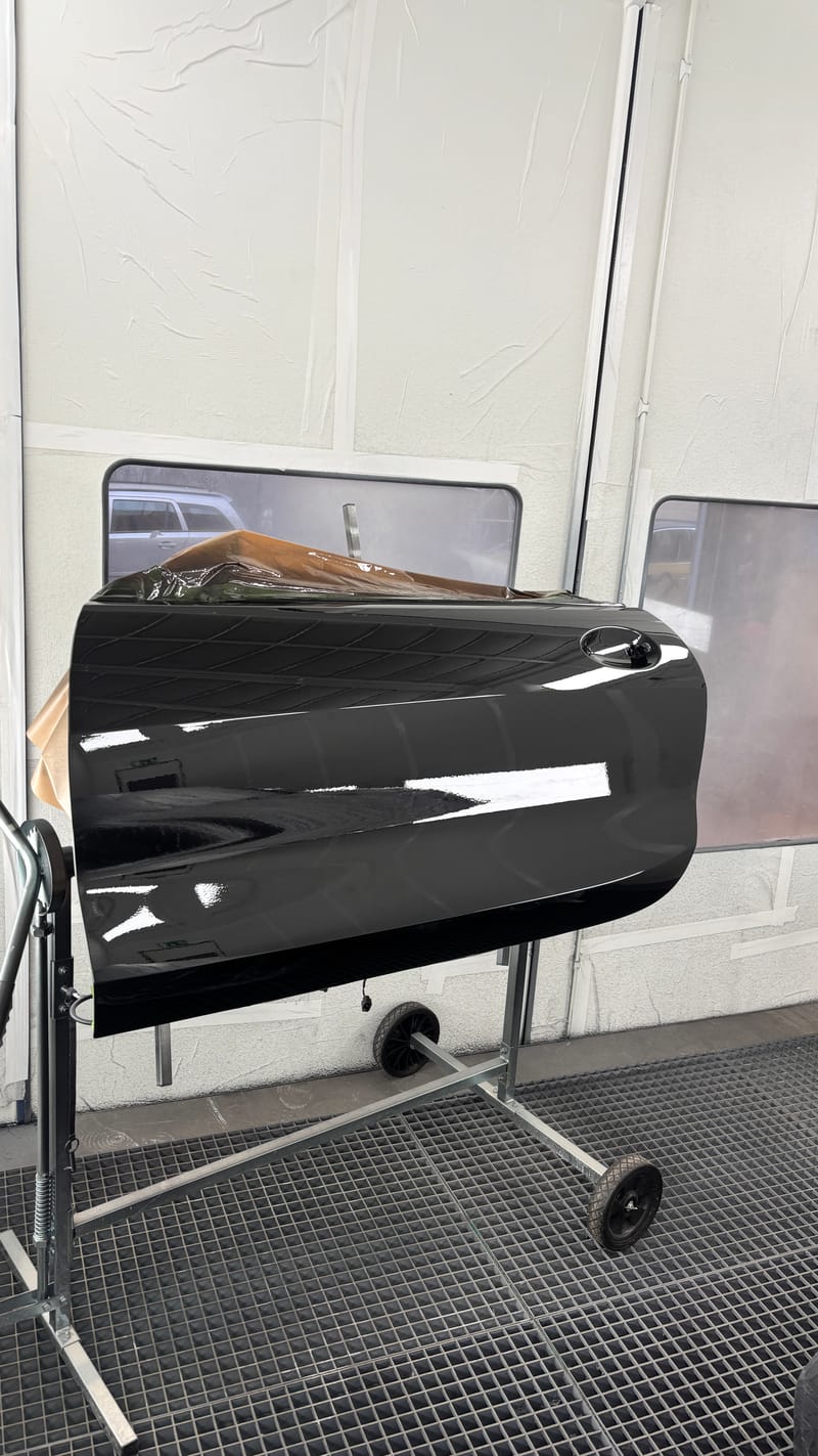Frisch lackierte schwarze Autotür auf dem Ständer in der Kabine