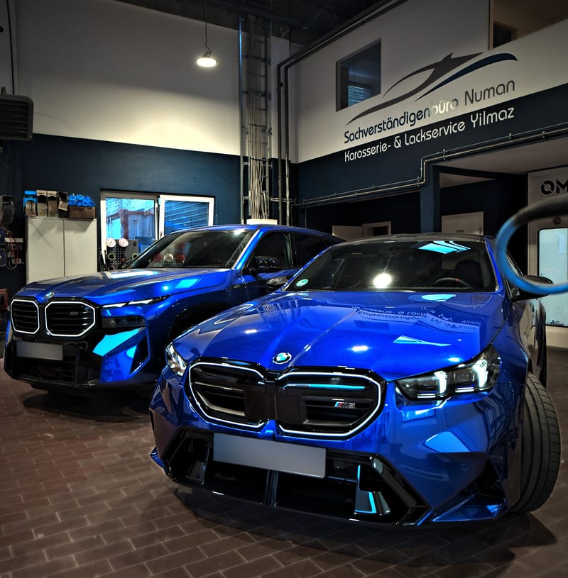 Blauer BMW M5 und BMW XM vor dem Firmenlogo