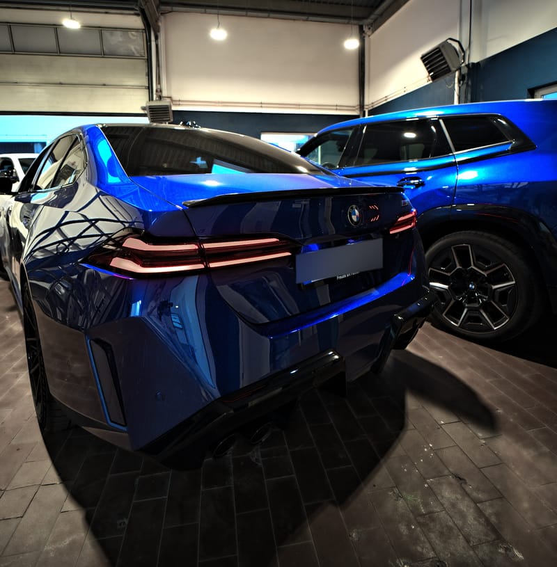 Heck eines blauen BMW M5 mit leuchtenden Rückleuchten