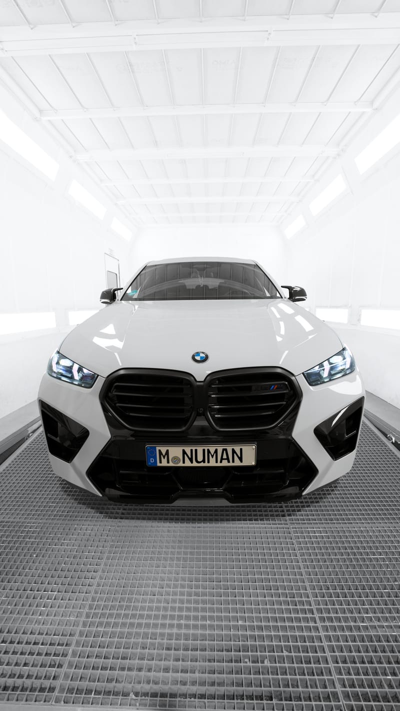 Weißer BMW X6 M in der hell ausgeleuchteten Lackierkabine